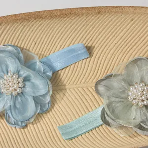 Detail van babyhaarbanden met organza bloemen en witte parels in het midden