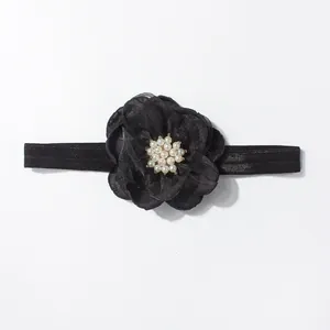 Detailweergave van een zwarte tule bloem baby haarband met witte parels in het midden