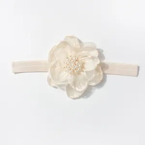 Detail van baby haarband met gelaagde organza bloem en parels op een elastische band