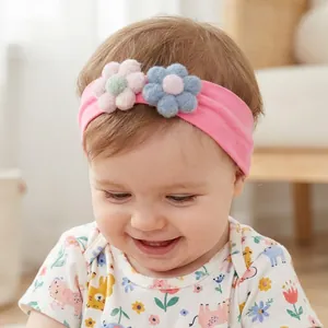 Close-up of a baby girl wearing a soft pink elastic headband with plush floral accents