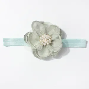 Detail van mintgroene baby haarband met gelaagde organza bloem en witte parelversiering