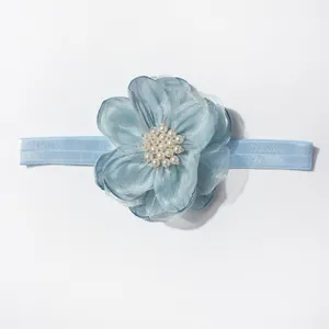 Detail van baby-hoofdband met lichtblauwe tulebloem en elegante witte parelkraaltjes
