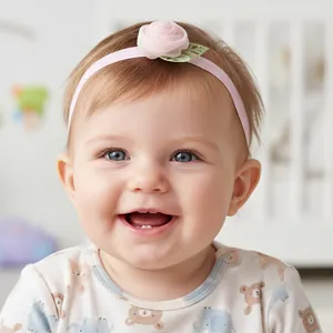 Detail of baby elastic headband featuring a pink mesh rose and green leaves on a toddler