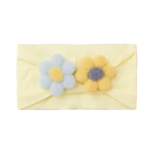 Detail of soft yellow nylon baby headband featuring handmade felt flower ornaments