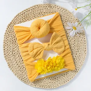 Lot de trois bandeaux jaunes pour bébé avec nœud et fleurs sur un tricot côtelé