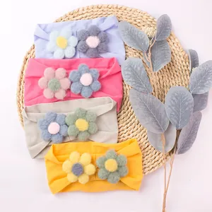 Elastic nylon baby headbands with colorful plush flowers on a rustic woven mat