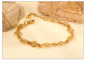 Detail view of a gold-plated link bracelet with oval loops on a natural rock background