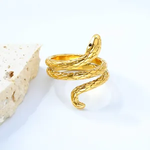 Golden spiral snake ring with textured scales and black bead eyes on white background