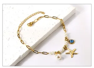 Détail de la chevillère en or 18k avec coquillage, perle et œil bleu sur pierre