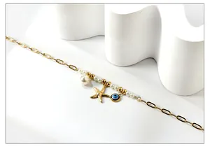 Détail d'une chevillère en or 18 carats avec perle, étoile de mer et œil grec bleu