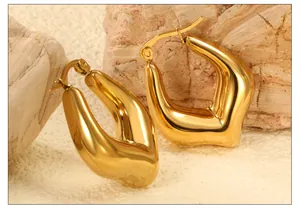 Macro shot of 18k gold plated U-shaped earrings with mirror finish on textured stone