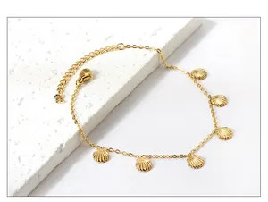 Close-up of golden stainless steel anklet with shell charms on a white stone base