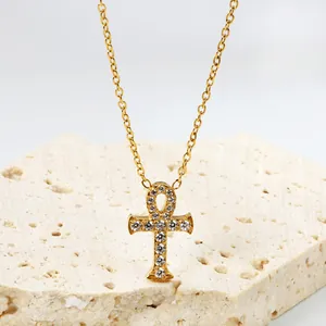 Gouden Ankh Kruis ketting met zirkonia pavé op een minimalistische stenen display