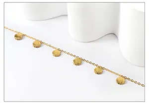 Close-up of golden stainless steel anklet featuring multiple delicate shell charms