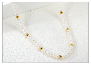 Detalle macro de perlas blancas y cuentas de metal bañadas en oro 18k en un collar