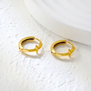 Detailed macro view of 18k gold hoop earrings with minimalist geometric star charm