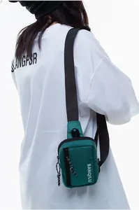 Detail of dark green crossbody chest bag with vertical zipper and adjustable strap