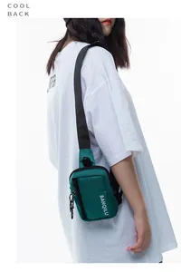 Detail of dark green nylon crossbody chest bag with white brand logo and strap