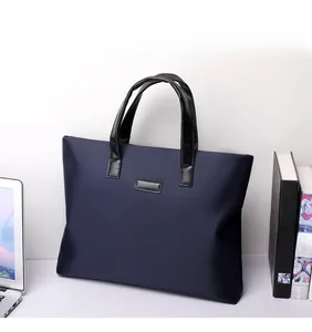 Detail of navy nylon tote bag with leather handles and rectangular patch on office desk