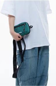 Close-up of green nylon crossbody phone bag with white BANG lettering on a model