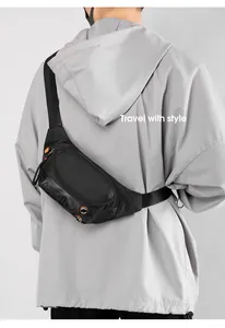 Rear view of black fashion chest bag with mesh detail and orange accents on a grey hoodie