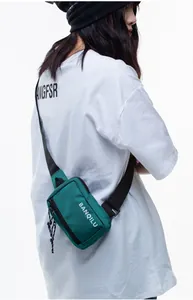 Close-up of a green crossbody phone bag with an adjustable strap on a male model