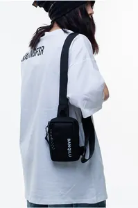 Street style view of a black nylon crossbody bag with vertical logo on oversized white t-shirt