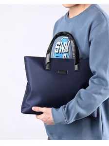 Detail of dark blue business briefcase with black leather handles held by a model