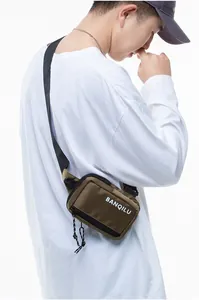 Close-up of olive nylon crossbody bag with adjustable strap and zip closure on model