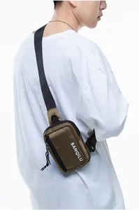 Detailed close-up of olive green nylon crossbody chest bag with white printed logo