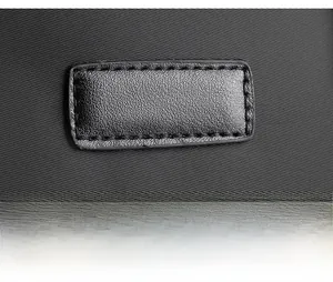 Macro detail of high-density nylon fabric and stitched leather patch on messenger bag