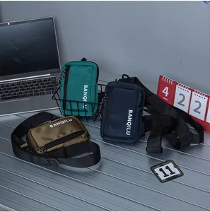 Three nylon crossbody bags in green, blue, and brown displayed on a modern metal desk