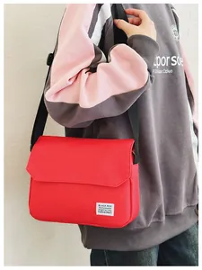 Model wearing a red canvas messenger bag with flap closure and adjustable strap