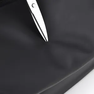 Macro detail of scratch-resistant fabric on black tactical leg bag tested with metal scissors