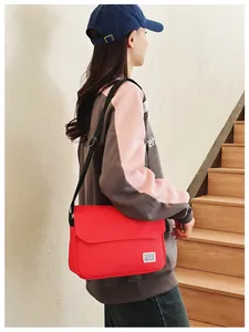 Close-up of red canvas messenger bag with brand label and adjustable black shoulder strap