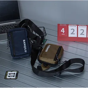 Detail of navy and olive nylon crossbody bags on a metal desk with adjustable straps