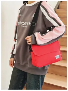 Close-up of red canvas messenger bag with flap closure and white woven brand label