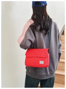 Rear view of model wearing a vibrant red canvas messenger bag with black wide strap