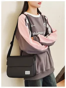 Close-up of black crossbody bag with flip cover and white label on stylish casual sweatshirt