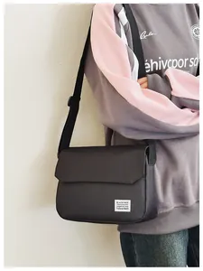 Neutral black messenger bag with adjustable strap shown worn on a male model for scale