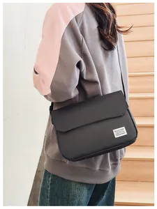 Detail view of black crossbody messenger bag with crossbody strap on casual outfit