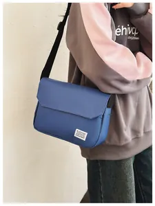 Blue canvas messenger bag shown on model featuring an adjustable strap and woven label