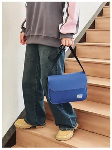Blue canvas messenger bag shown on model featuring adjustable strap and flap closure