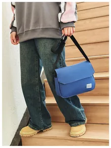 Detailed view of a blue canvas messenger bag featuring a white logo patch and black strap