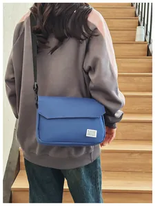 Detail view of the navy blue canvas messenger bag with adjustable strap and brand tag