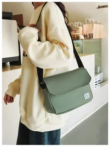 Close-up of a light green messenger bag with a black shoulder strap and flap design