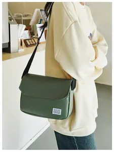 Detail of dark green canvas messenger bag featuring adjustable strap and woven brand tag