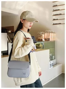 Minimalist lavender messenger bag with adjustable black strap shown in a cafe setting
