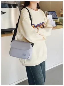 Lifestyle view of a light purple canvas messenger bag with flap and black strap