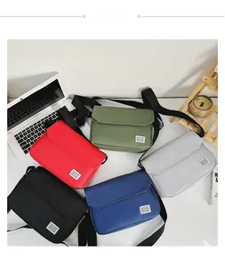 Flat lay of nylon messenger bags in five colors with adjustable straps on a desk